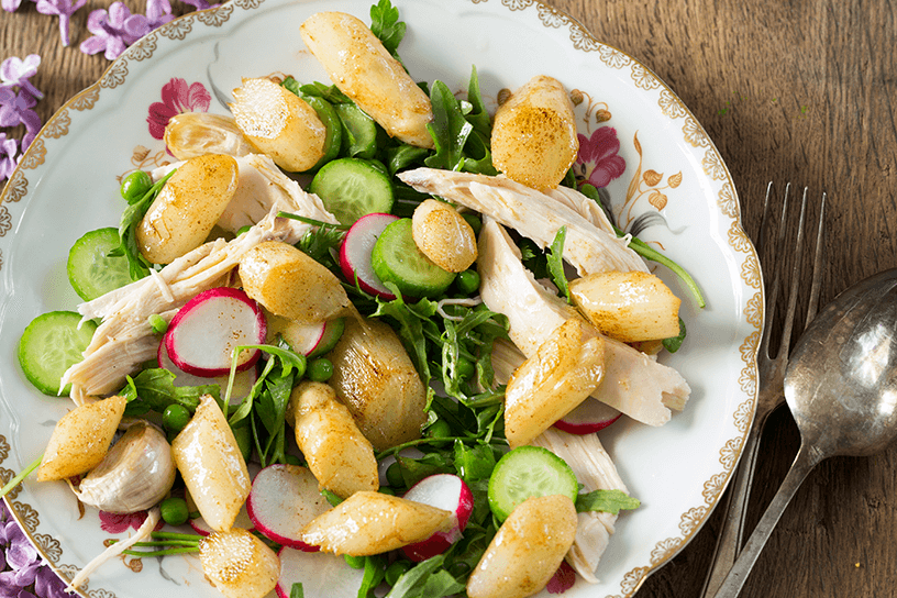 bord met salade van gebakken asperges, radijsjes, komkommer en kipfilet
